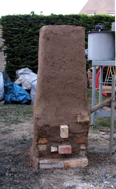 Façade avant du bas - fourneau de type japonais (16ème siècle) en cours de finition. Les briques centrales émergentes seront les premières retirées pour permettre l'écoulement du laitier. <br />Briques réfractaires , paille , terre , kaolin